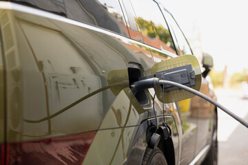 Close up shot of electric car battery plugged into clean energy power source to recharge. EV SUV vehicle battery powering electric motor being left to charge in parking lot