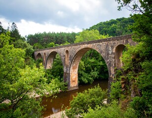 Fototapeta premium Stone arch bridge over a river in a lush valley