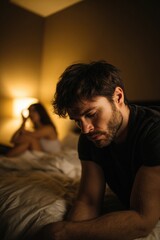 Obraz premium Pensive man on bed showing male potency challenges, intimate difficulties, relationship troubles with female partner in dimly lit bedroom scene.