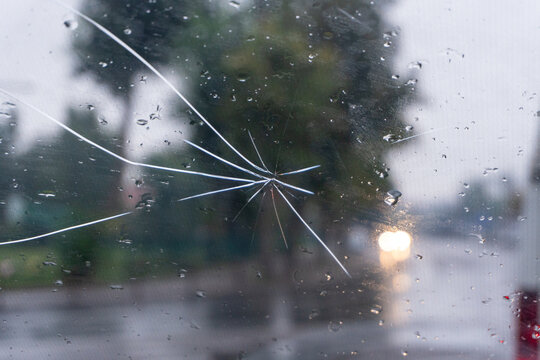 Cracked windshield with raindrops visible on a rainy day in a city