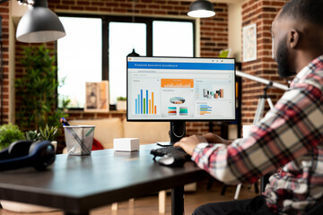 African american businessman working from home, reviewing business fiscal report and preparing...