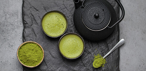 Traditional japanese matcha tea ceremony set on a dark slate plate, including a black iron teapot,...