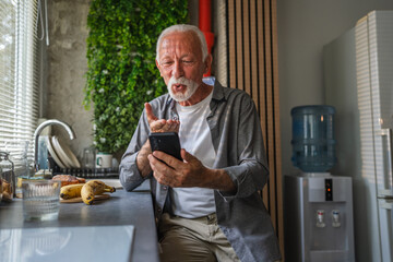 Senior man sending a kiss on a video call in the kitchen