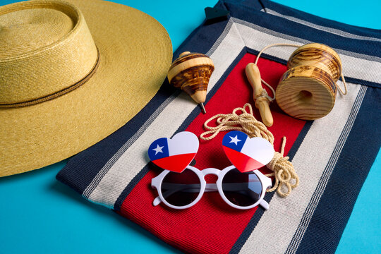 Traditional chilean objects celebrating chilean national holidays with a huaso hat, a spinning top, an emboque, and heart-shaped glasses with the chilean flag
