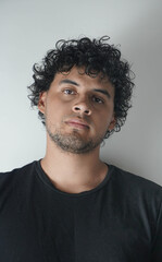 Obraz premium Latino boy with curly hair on a white background and a black t-shirt