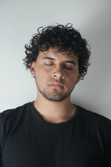 Obraz premium Latino boy with curly hair on a white background and a black t-shirt
