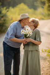 An elderly man gives his wife a bouquet of flowers on their wedding anniversary