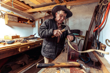 Adulto mayor artesano de talabartería trabajando en su taller artesanal en Zuleta, Imbabura,...