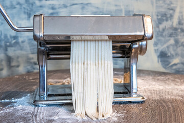 Obraz premium Flour-Dusted Manual Pasta Maker with Raw Dough in Rustic Kitchen Setting