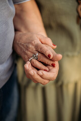 Elderly man in love holds and caresses tender hands of his beautiful woman, couple confesses love and fidelity, close-up