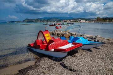 Colorful pedal boats on a scenic beach.