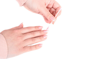 Female hands cleaning nails with manicure using pink cotton swab.