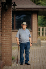 Grandfather in a hat. Portrait of a very old Caucasian man. Portrait: elderly, lonely, elderly, with many wrinkles on his face. Close-up of a thoughtful old man standing alone outdoors.