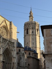 Central square in the historic center of Valencia, Spain. Gothic Valencia Cathedral against blue sky on a sunny day in Plaza de la Virgen