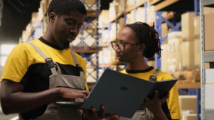 Large business warehouse staff handling order fulfillment with laptop data, handling distribution...