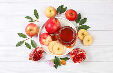 Creative composition for the Jewish holiday Ro Hashanah with a place for congratulations. Layout with traditional symbols of the Jewish New Year, template with honey, apples, pomegranate and flowers