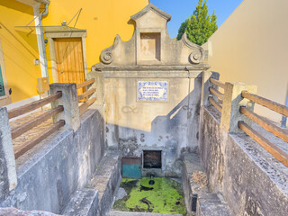 The historic Fonte da Mota in Ovar, Portugal, an old stone fountain with algae-covered water,...