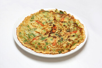 High resolution photo of Korean vegetable pancake (pajeon) garnished with sliced red chili peppers on white background. A colorful and traditional Korean savory dish.