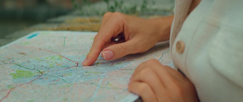 Closeup of hand pointing to destination on Milan city map outdoors during Italy trip