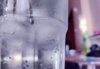 Close-up of a cold glass filled with ice cubes. Cold water is covered in condensation droplets. The...