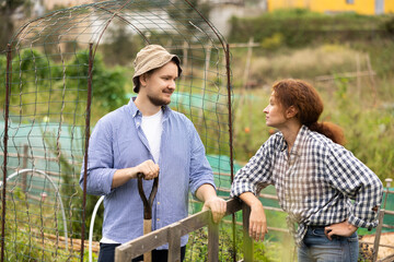European woman in checkered shirt, chatting sweetly with man neighbor. Rustic setting, young woman...