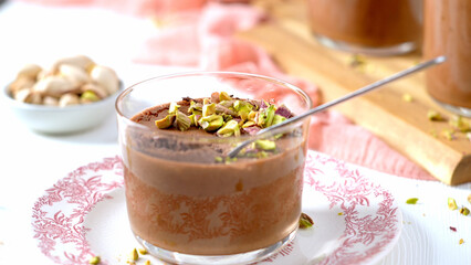 A glass of chocolate mousse topped with pistachios