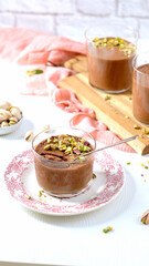 A chocolate mousse dessert topped with pistachios in a vertical format