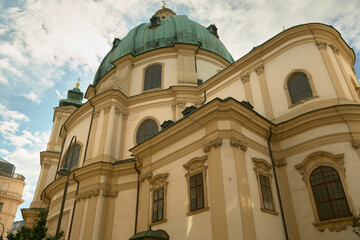 Fototapeta premium Wide-angle view of a cathedral in Vienna featuring a large green dome and a smaller secondary dome, highlighting architectural grandeur under a clear blue sky.