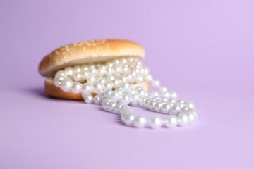 Burger with pearl necklace on lilac background, closeup