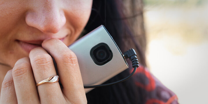 Woman Talking On Vintage Phone With Ring Covering Mouth Outdoors