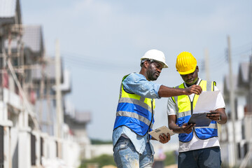 Two professional Black engineers collaborating on a building project. A skilled architect discusses...