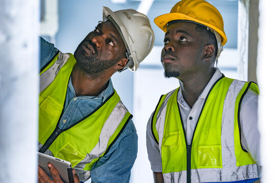 Two professional Black engineers collaborating on a building project. A skilled architect discusses plans with his colleague, representing diversity and expertise in the construction industry. - Powered by Adobe