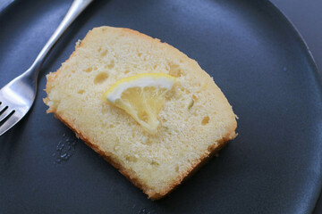 Slice Lemon pound cake on black plate. homemade dessert. Delicious breakfast, traditional English tea time.