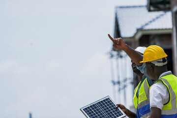 A senior electrician provides hands on training to a young apprentice on solar technology. Building...