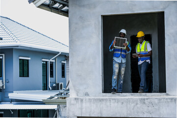 A senior electrician provides hands on training to a young apprentice on solar technology. Building...