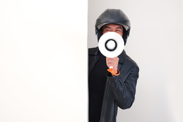 Motorcycle rider wearing helmet peeking from behind a wall give announcement using megaphone