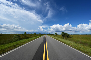 Fototapeta premium Bright summer cloudscape over Main Park Road in Everglades National Park, Florida.