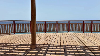 Enjoy a Scenic Ocean View from a Wooden Deck with Shades that Create a Relaxing Ambiance