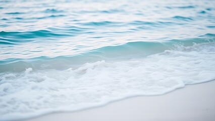 Fototapeta premium Calm blue ocean waves gently rolling onto a white sandy beach, evoking tropical serenity.