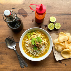 Indonesian soto ayam with sambal, lime, and soy sauce bottles