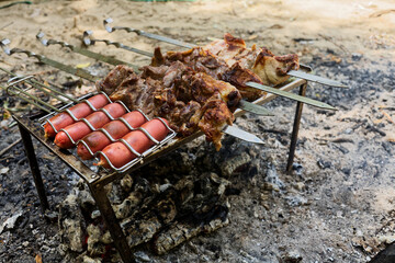 Grilled Meat and Sausages Cooking on Metal Skewers over Open Fire