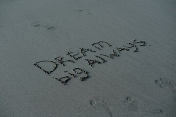 Dream big always written text in sand in sunlight