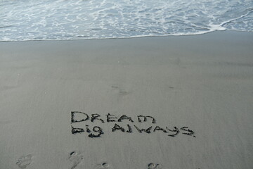 Fototapeta premium Dream big always written in sand in sunlight