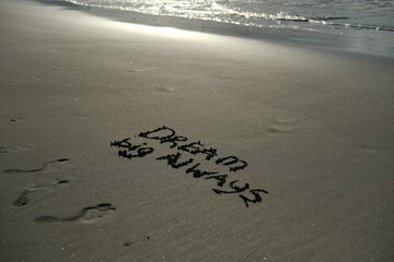 Dream big always written in sand in sunlight