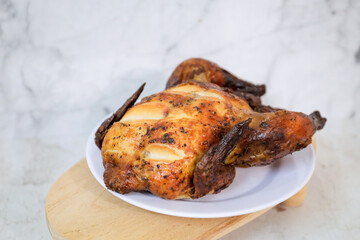 Roasted chicken whole on white plate	

