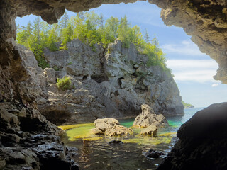 Scenic view from inside a cave overlooking turquoise waters in Tobermory, Ontario.