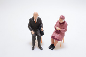 Figures of Elderly Couple Sitting and Conversing on Chairs