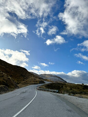 Scenic mountain road under blue sky with clouds