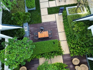 This photo showcases a beautifully designed outdoor patio garden, blending natural elegance with modern comfort. A central wooden dining table with four chairs invites gatherings, while surrounding 