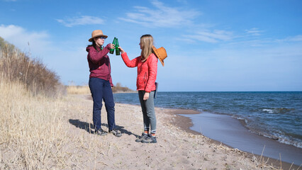 The students celebrate the end of the session. Two women are standing on the beach with beer...